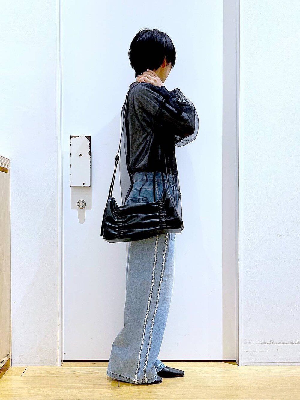 ブラック系のショルダーバッグ、ブラック系のパンプス、ブルー系のデニムパンツを着用したレディースの春コーディネートの4枚目の写真