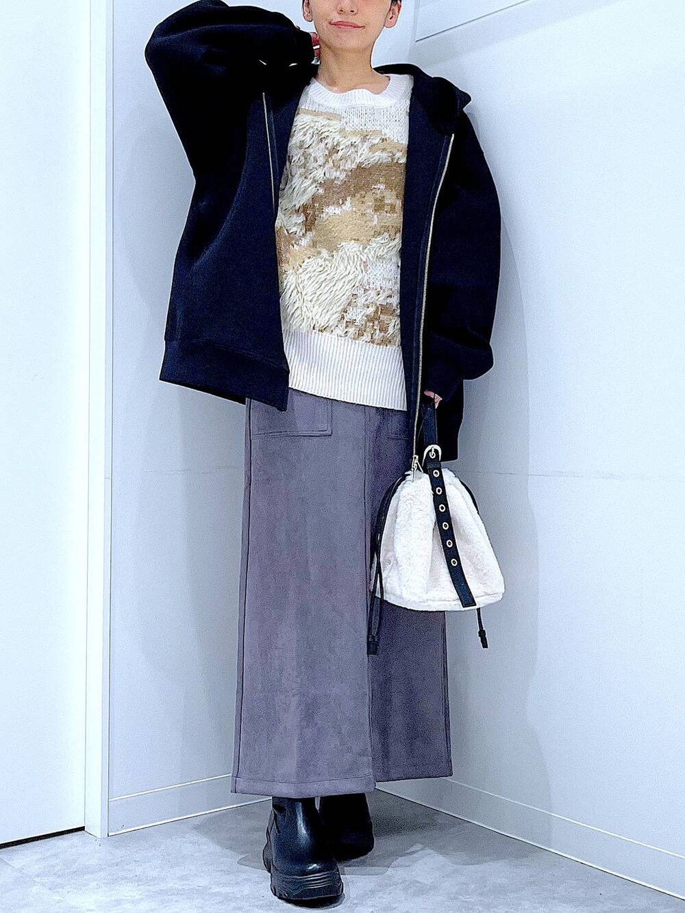 ホワイト系のハンドバッグ、ブラック系のブーツ、グレー系のスカートを着用したレディースの冬コーディネートの6枚目の写真