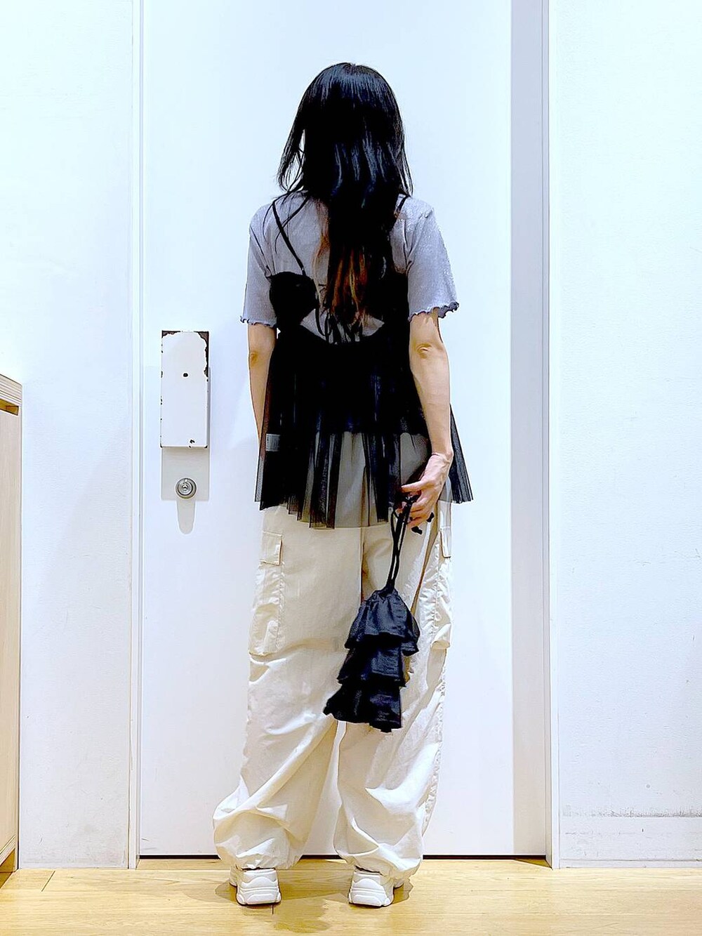 ブラック系のショルダーバッグ、ホワイト系のカーゴパンツ、ブラック系のキャミソールを着用したレディースの夏コーディネートの5枚目の写真