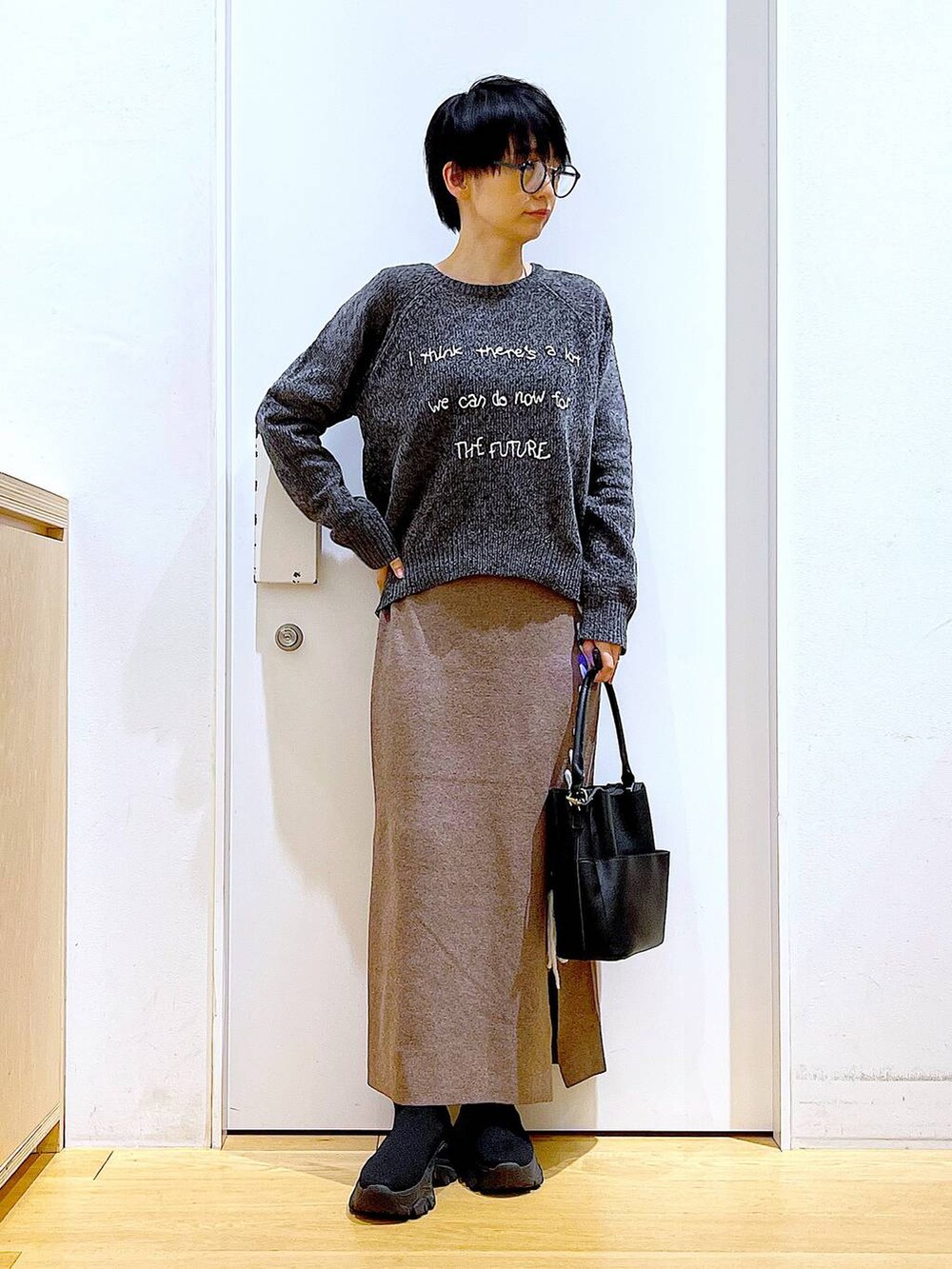 ブラック系のブーツ、ブラック系のショルダーバッグ、ブラウン系のスカートを着用したレディースの冬コーディネートの2枚目の写真