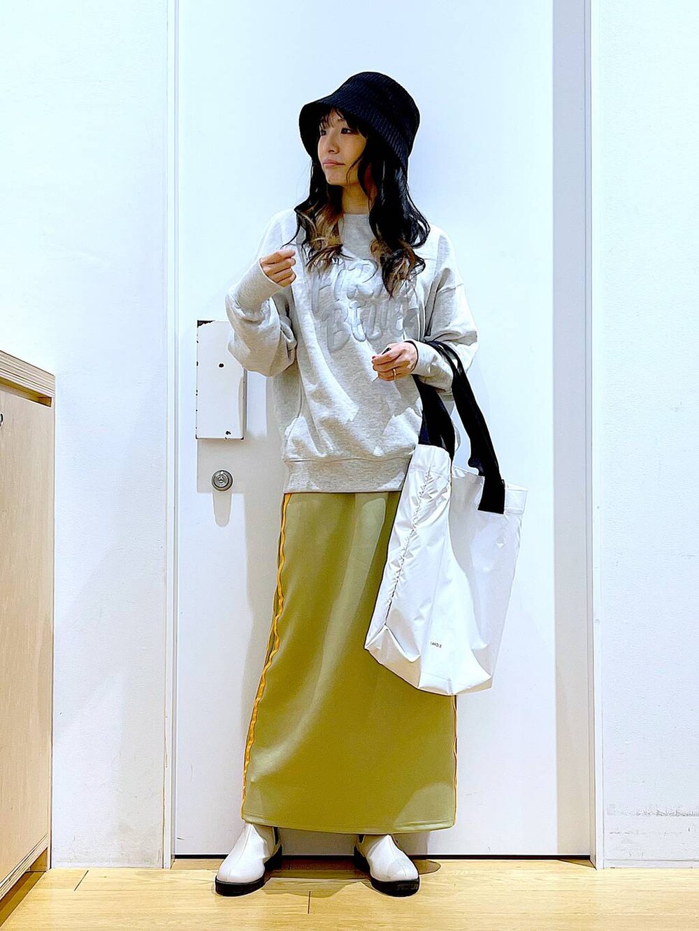 ベージュ系のスウェット、ベージュ系のブーツ、ホワイト系のトートバッグを着用したレディースの冬コーディネートの2枚目の写真