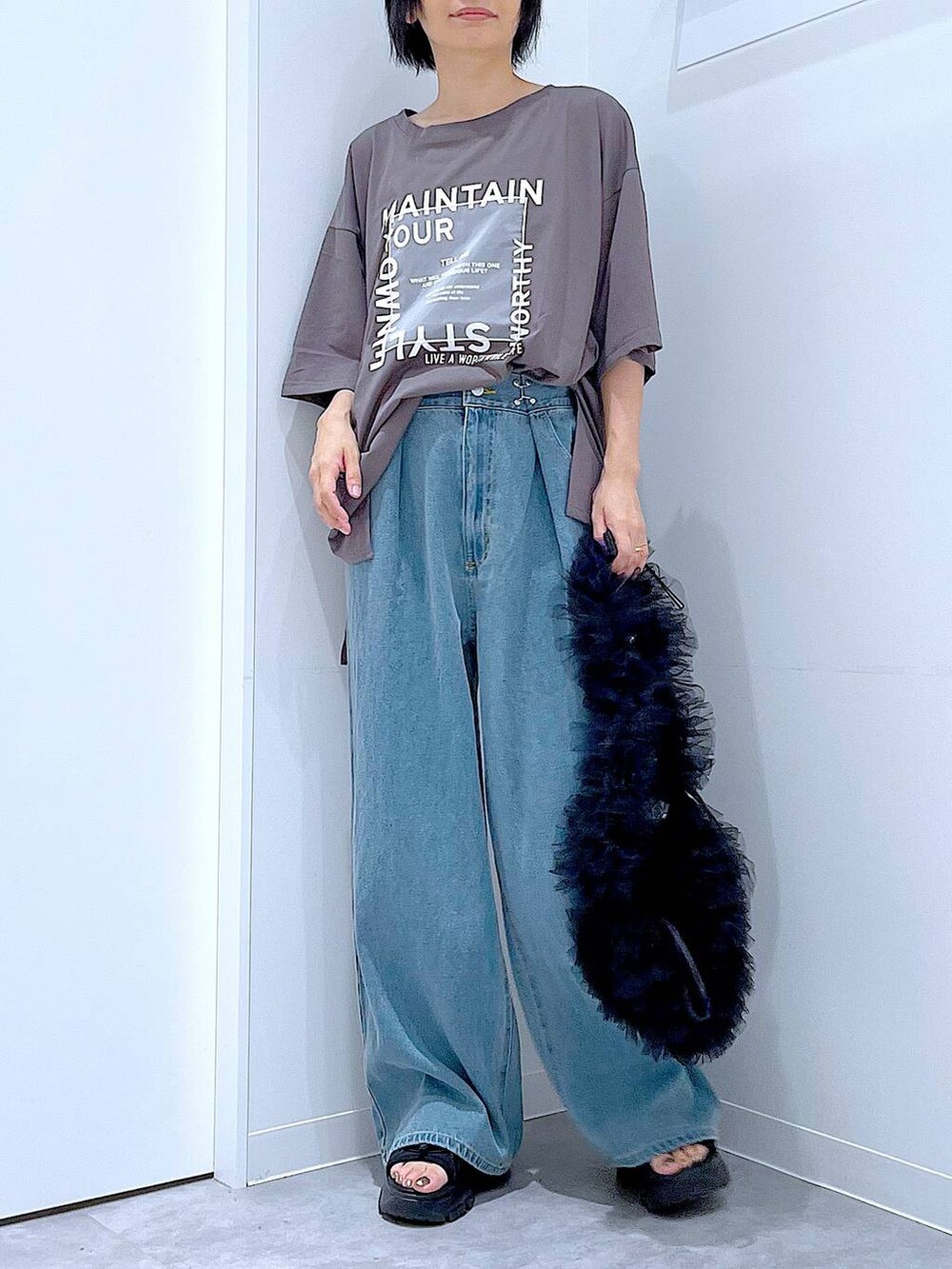 ブラック系のショルダーバッグ、ブラック系のスニーカー、ブルー系のデニムパンツを着用したレディースの秋コーディネートの6枚目の写真