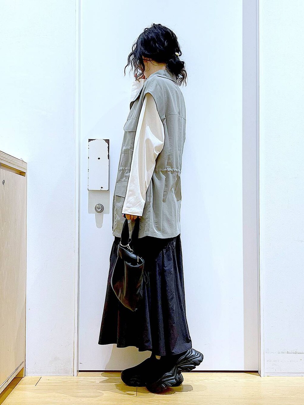 ブラック系のショルダーバッグ、ブラック系のスニーカー、ブラック系のスカートを着用したレディースの春コーディネートの3枚目の写真