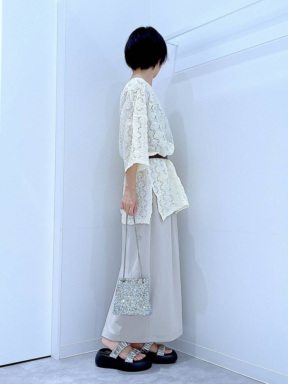 シルバー系のサンダル、ベージュ系のスカート、シルバー系のショルダーバッグを着用したレディースの夏コーディネートの4枚目の写真