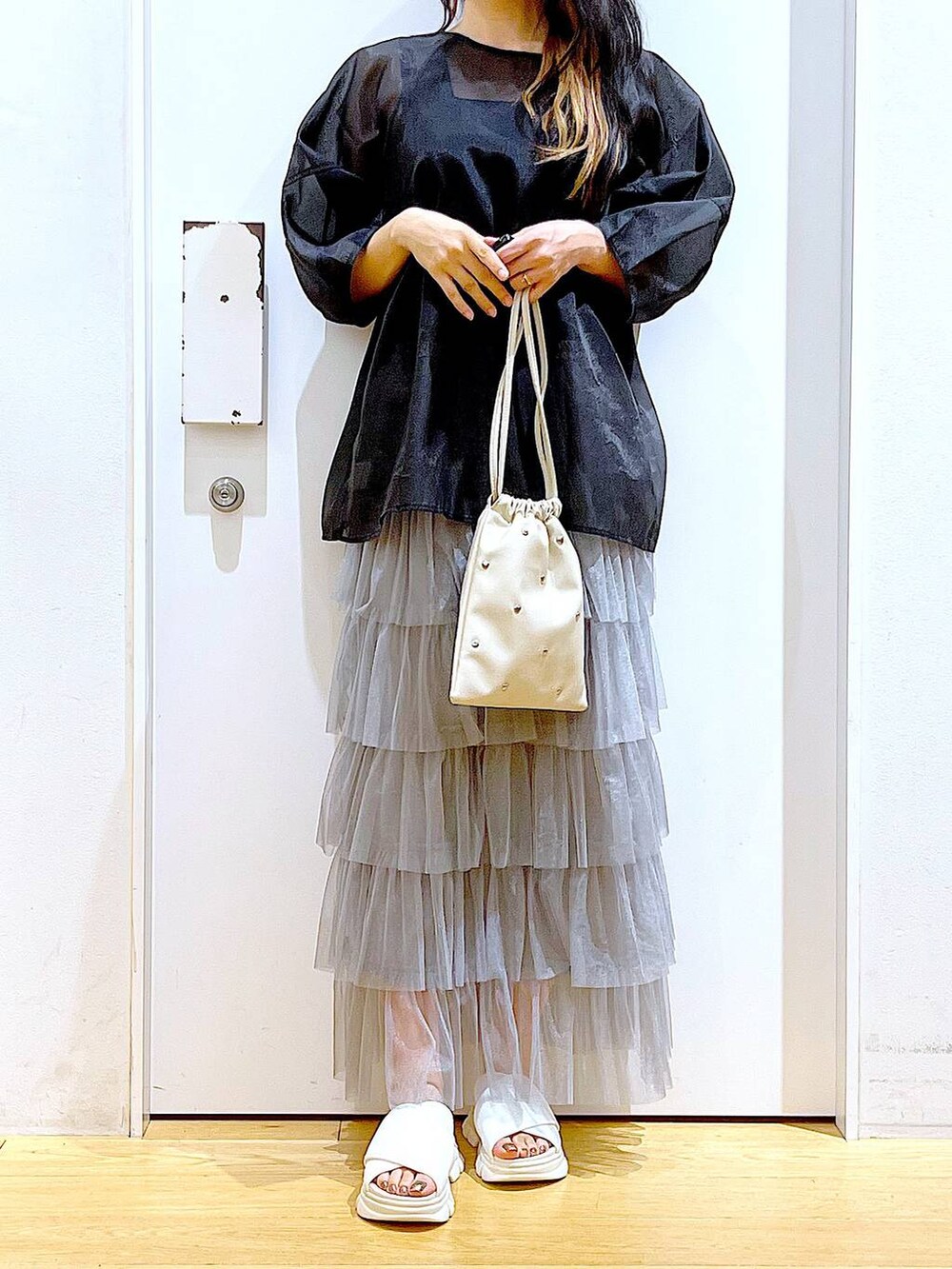 ホワイト系のサンダル、ブラック系のニット/セーター、ホワイト系のショルダーバッグを着用したレディースの夏コーディネートの6枚目の写真