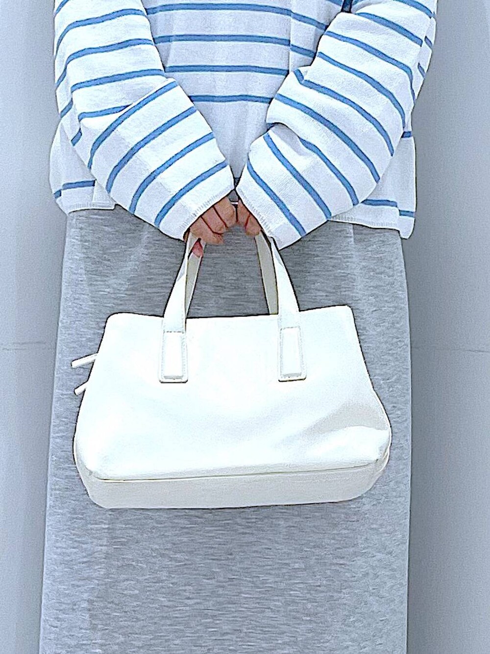 ホワイト系のボストンバッグ、グレー系のスカートを着用したレディースの春コーディネートの9枚目の写真