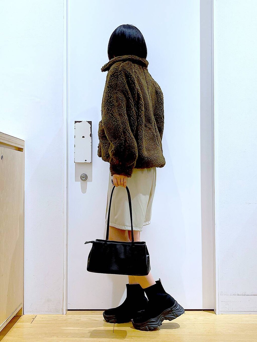 ブルー系のニット/セーター、ブラック系のトートバッグ、ブラック系のブーツを着用したレディースの冬コーディネートの3枚目の写真