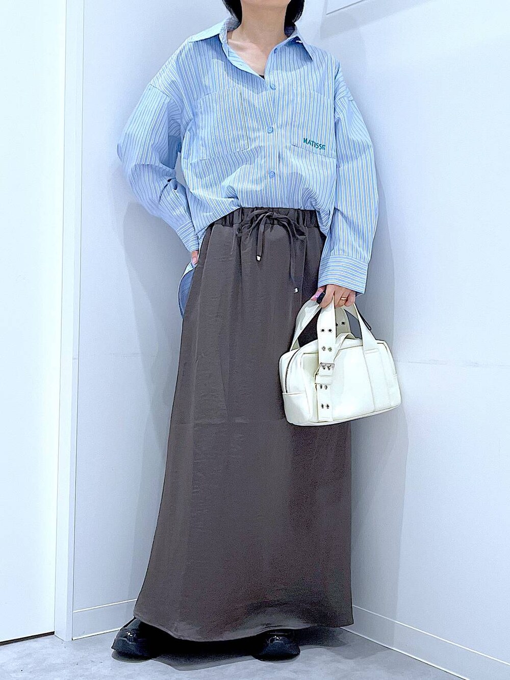 ブラック系のローファー、ホワイト系のショルダーバッグ、グレー系のスカートを着用したレディースの秋コーディネートの6枚目の写真