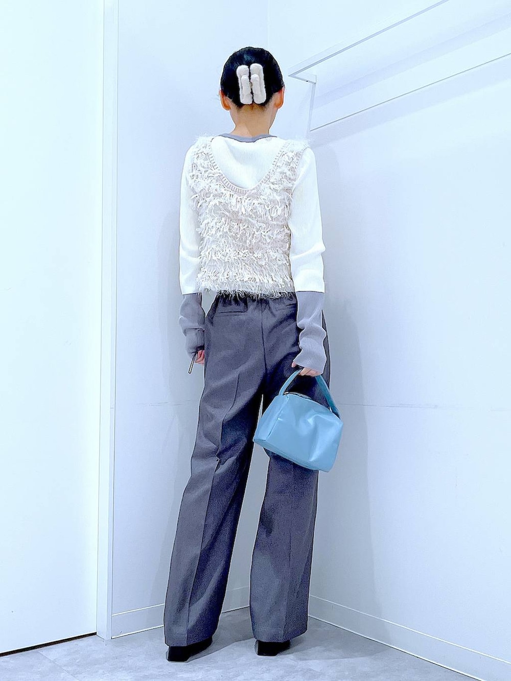 ブラック系のブーツ、グレー系のスラックス、ホワイト系のベストを着用したレディースの冬コーディネートの5枚目の写真