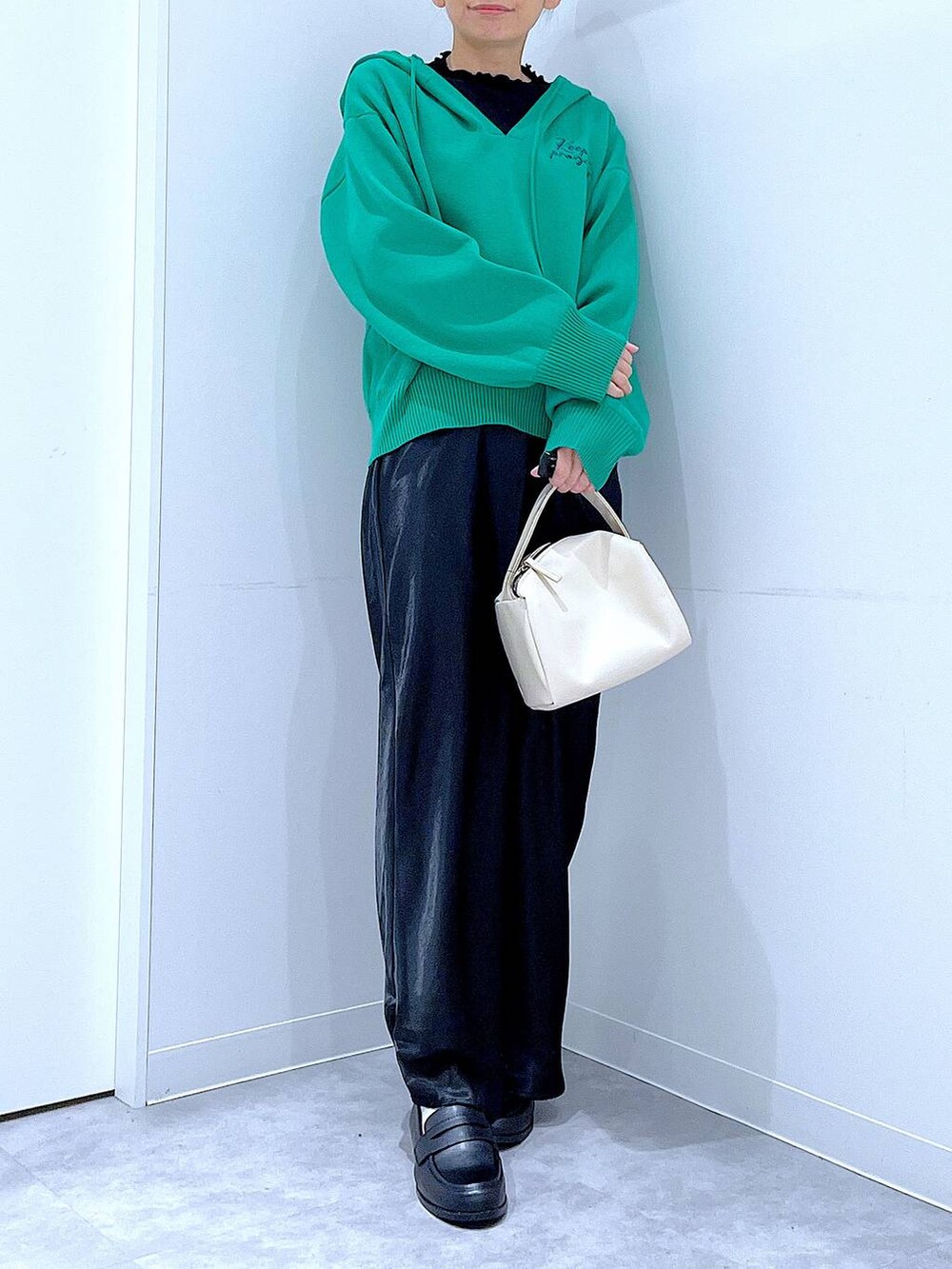 ブラック系のTシャツ/カットソー、ホワイト系のショルダーバッグ、グリーン系のニット/セーターを着用したレディースの春コーディネートの6枚目の写真