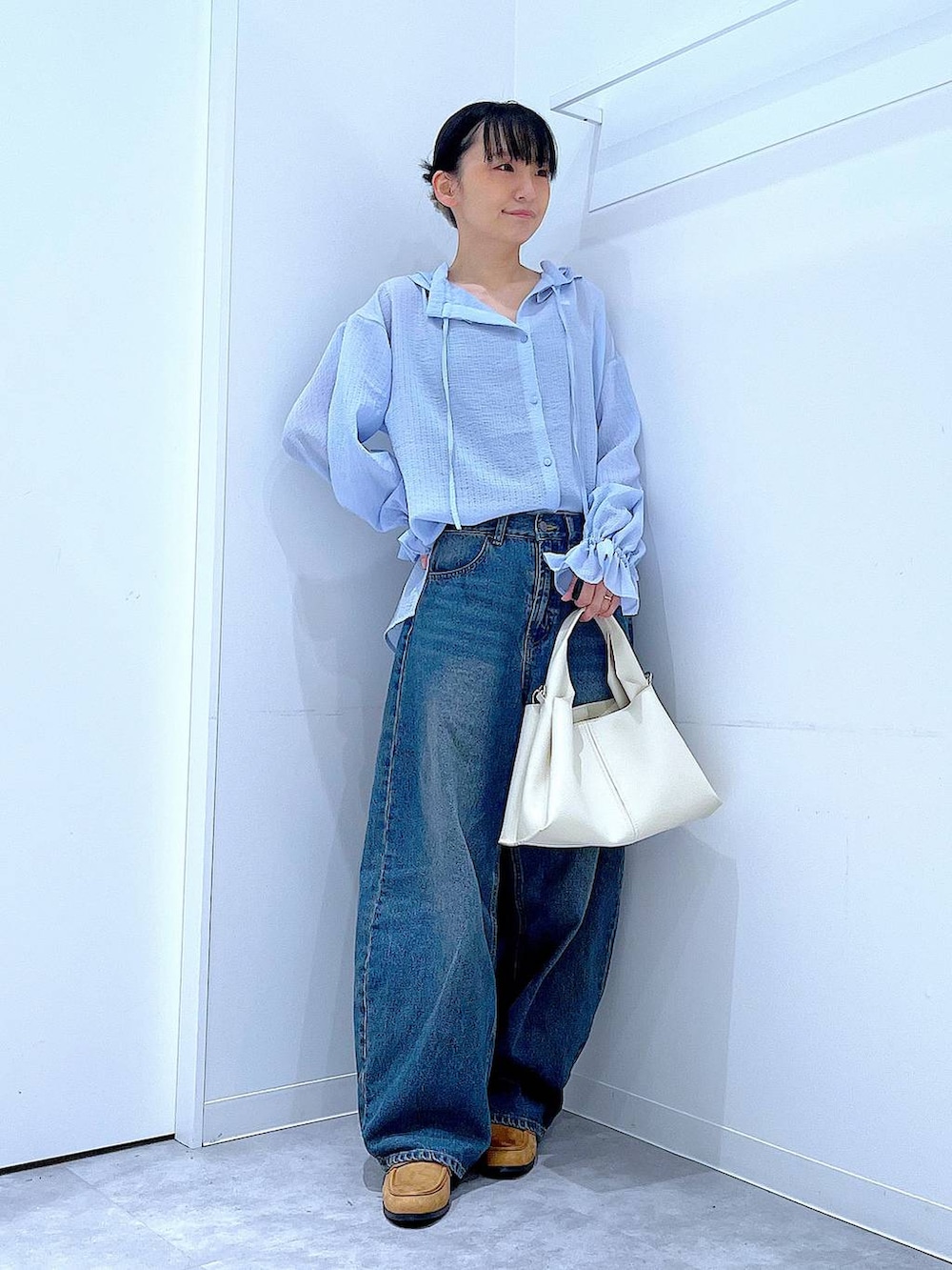 ブルー系のデニムパンツ、ベージュ系のローファー、ホワイト系のトートバッグを着用したレディースの春コーディネートの2枚目の写真