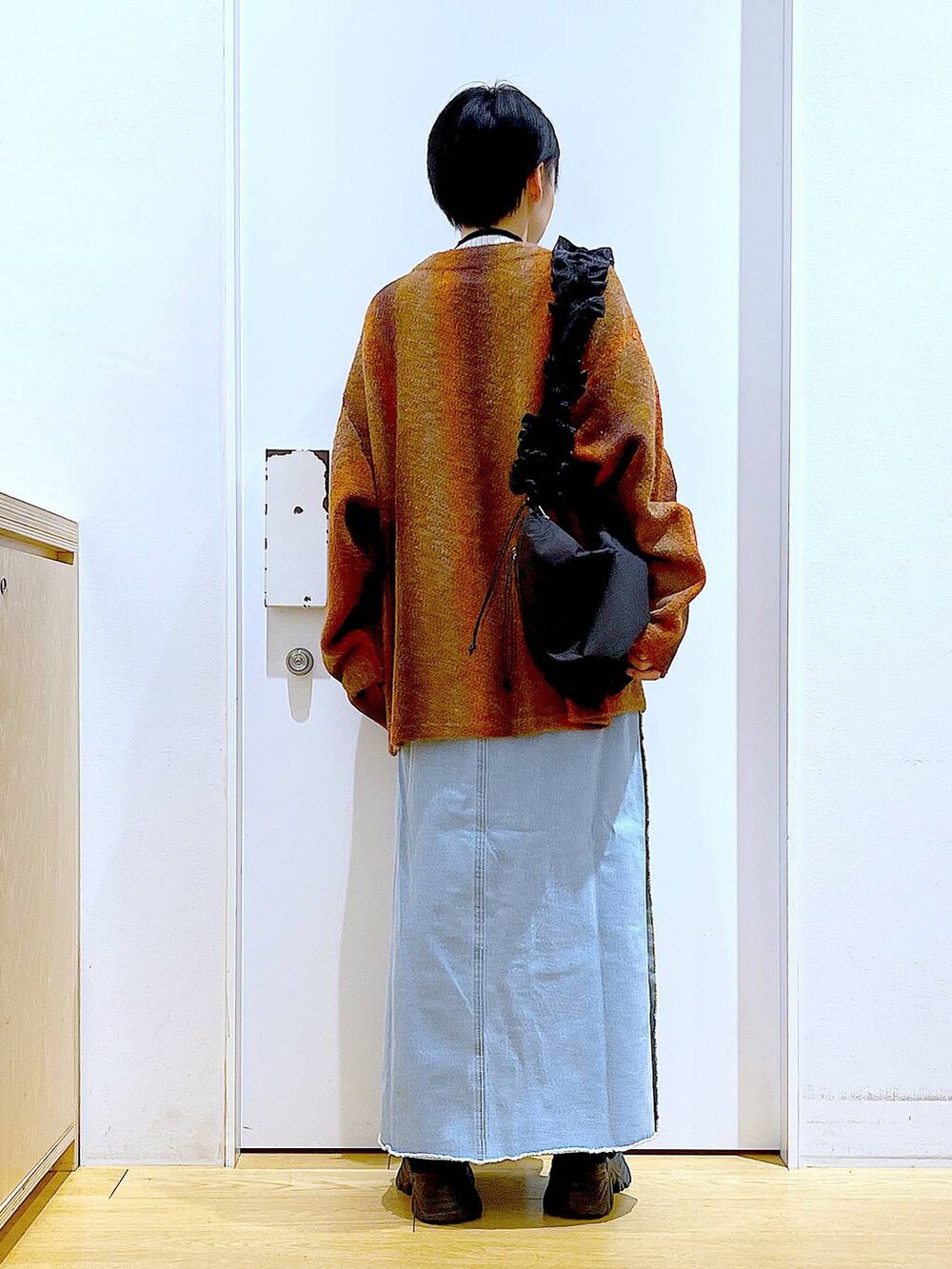 ベージュ系のニット/セーター、ブラック系のショルダーバッグ、ブルー系のデニムスカートを着用したレディースの冬コーディネートの5枚目の写真