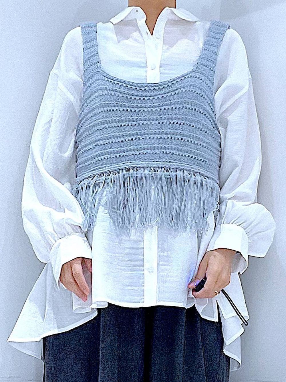 ブラック系のブーツ、ブルー系のベスト、ホワイト系のショルダーバッグを着用したレディースの春コーディネートの7枚目の写真