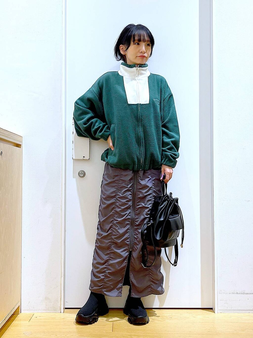 ブラック系のバックパック/リュック、グレー系のスカート、ブラック系のブーツを着用したレディースの冬コーディネートの2枚目の写真