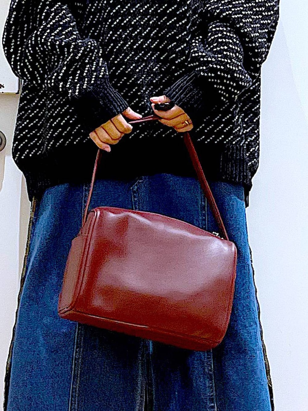 レッド系のショルダーバッグ、ブルー系のデニムスカート、ブラック系のニット/セーターを着用したレディースの冬コーディネートの9枚目の写真