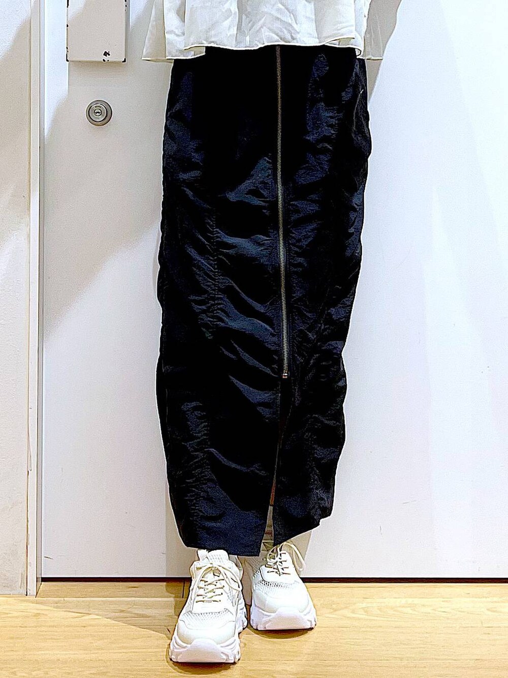 ブラック系のスカート、ブラック系のショルダーバッグ、ホワイト系のスニーカーを着用したレディースの春コーディネートの8枚目の写真