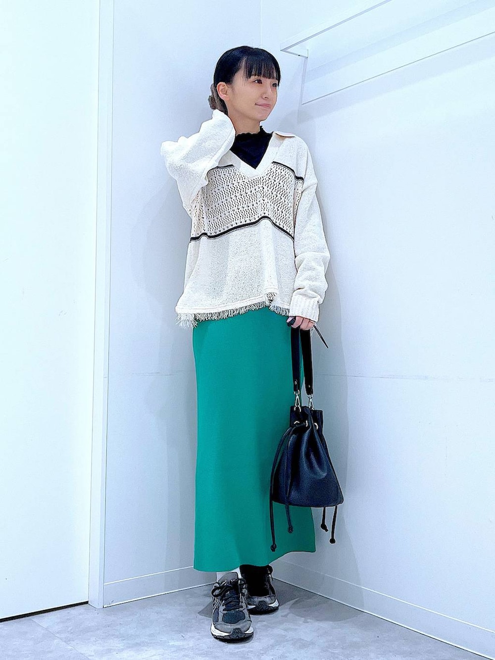 ブラック系のTシャツ/カットソー、グリーン系のスカート、ホワイト系のニット/セーターを着用したレディースの冬コーディネートの2枚目の写真