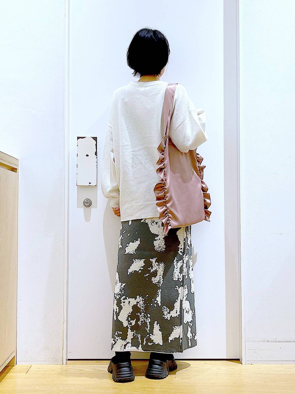 グレー系のスカート、ブラック系のブーツ、ベージュ系のニット/セーターを着用したレディースの秋コーディネートの5枚目の写真