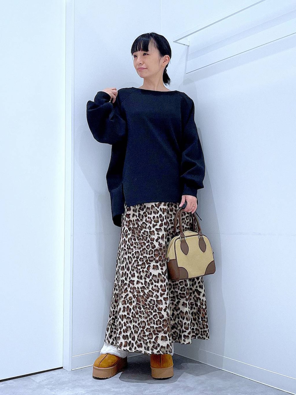 イエロー系のスリッポン、ベージュ系のハンドバッグ、ブラウン系のスカートを着用したレディースの秋コーディネートの2枚目の写真