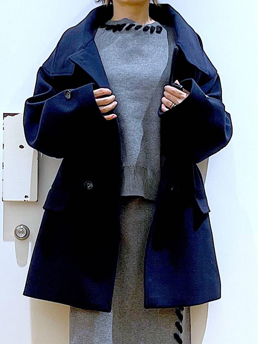 ブルー系のステンカラーコート、ホワイト系のハンドバッグ、ブラック系のブーツを着用したレディースの冬コーディネートの7枚目の写真
