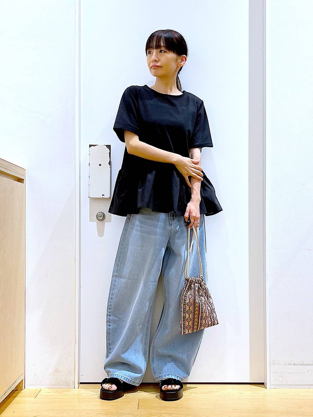 ピンク系のショルダーバッグ、ブルー系のデニムパンツ、ブラック系のTシャツ/カットソーを着用したレディースの夏コーディネートの2枚目の写真