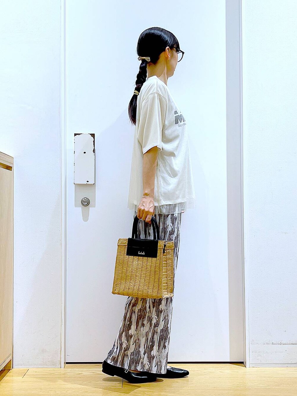 ホワイト系のTシャツ/カットソー、ブラック系のパンプス、ベージュ系のショルダーバッグを着用したレディースの夏コーディネートの4枚目の写真