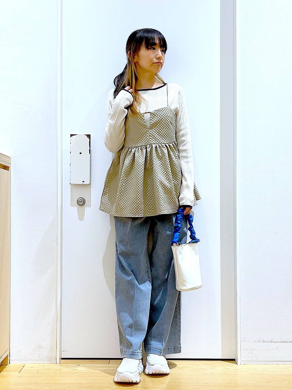 ブルー系のショルダーバッグ、ブルー系のデニムパンツ、ベージュ系のニット/セーターを着用したレディースの春コーディネートの2枚目の写真