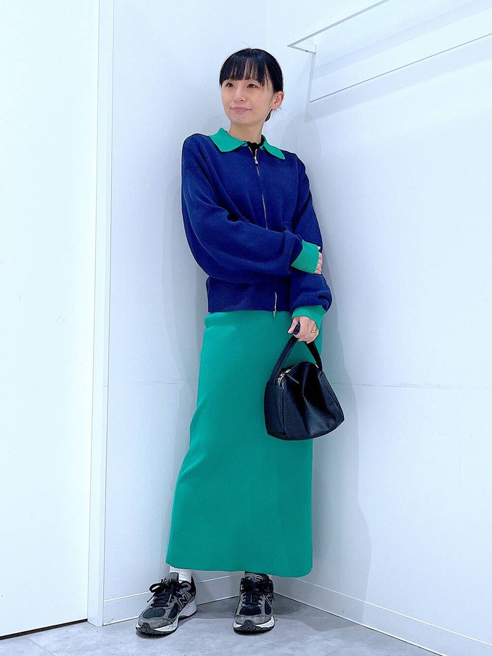 ブラック系のショルダーバッグ、ブルー系のカーディガン/ボレロ、グリーン系のスカートを着用したレディースの春コーディネートの2枚目の写真