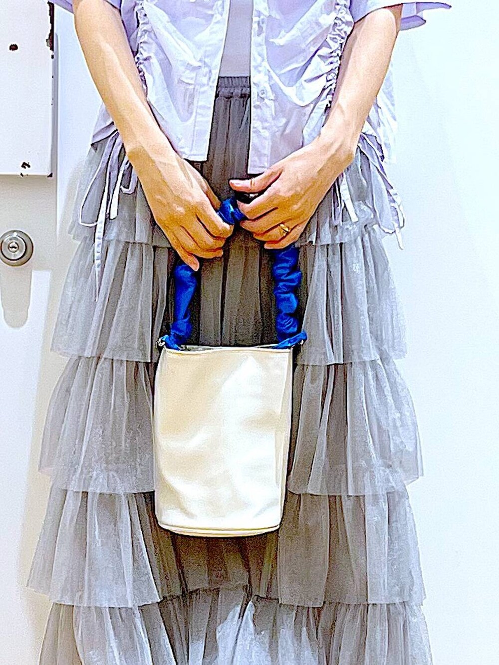 ブルー系のショルダーバッグ、ホワイト系のサンダル、グレー系のスカートを着用したレディースの夏コーディネートの9枚目の写真