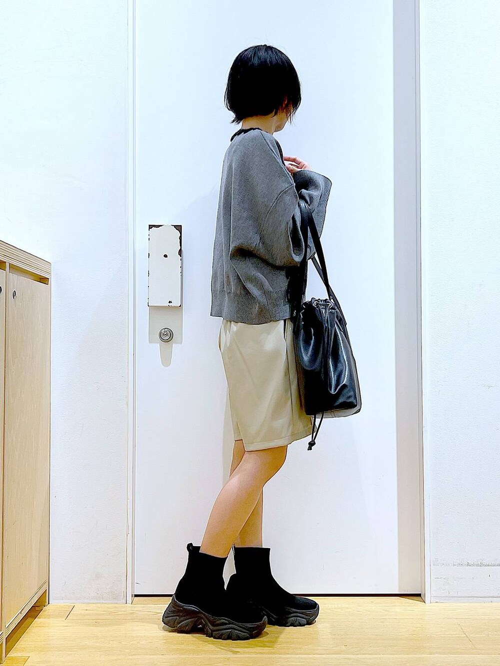 ブラック系のトートバッグ、ブラック系のブーツ、グレー系のニット/セーターを着用したレディースの冬コーディネートの4枚目の写真