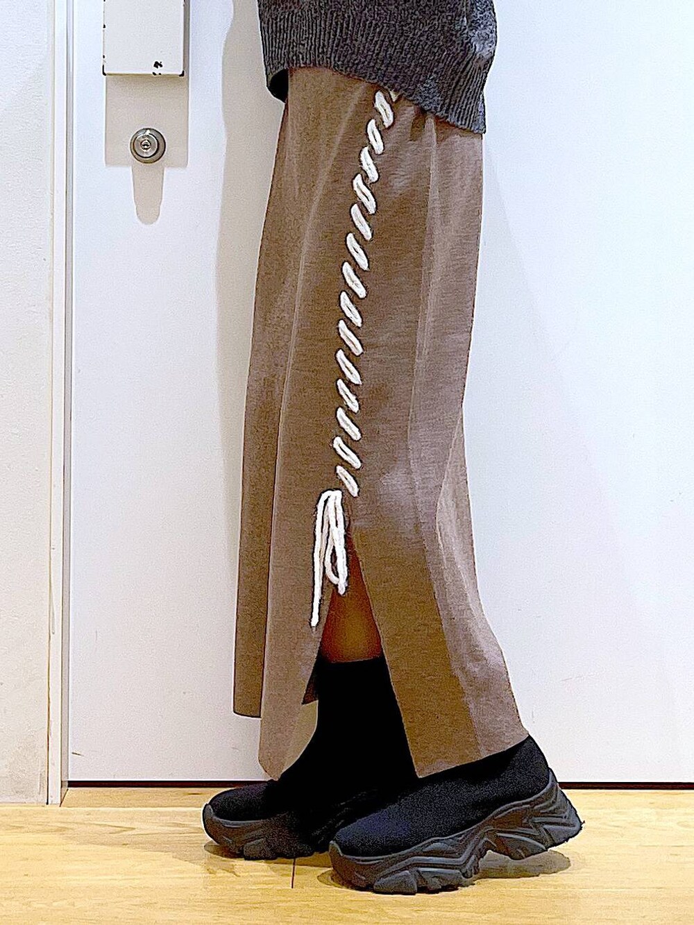 ブラック系のブーツ、ブラック系のショルダーバッグ、ブラウン系のスカートを着用したレディースの冬コーディネートの8枚目の写真