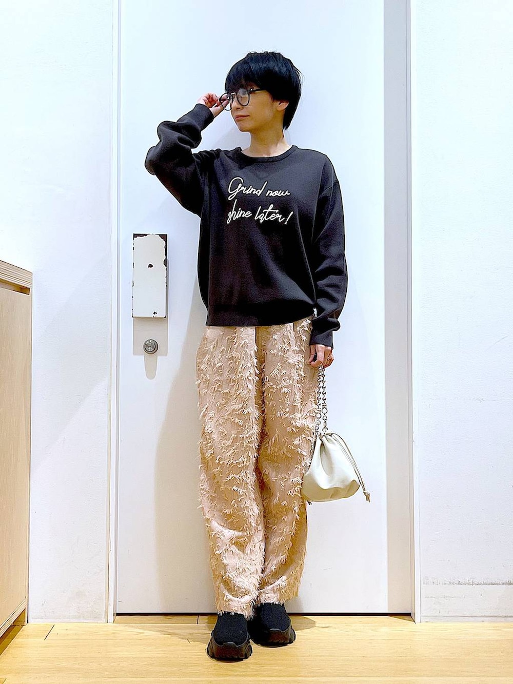 ベージュ系のショルダーバッグ、ブラック系のブーツ、グレー系のニット/セーターを着用したレディースの春コーディネートの2枚目の写真