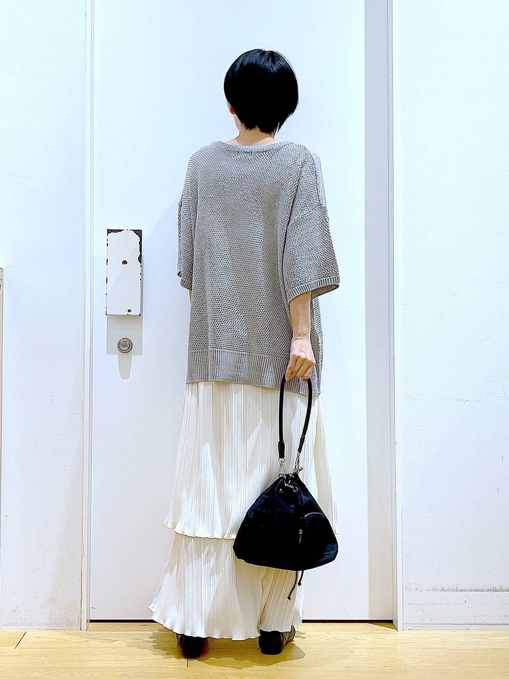 ブラック系のパンプス、ホワイト系のスカート、グレー系のニット/セーターを着用したレディースの春コーディネートの5枚目の写真