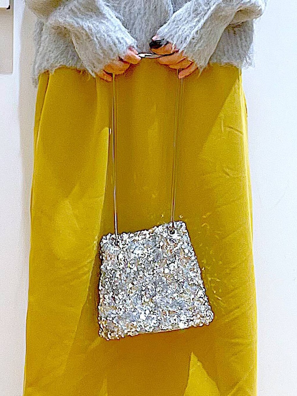 グレー系のニット/セーター、ブラック系のブーツ、イエロー系のスカートを着用したレディースの冬コーディネートの9枚目の写真