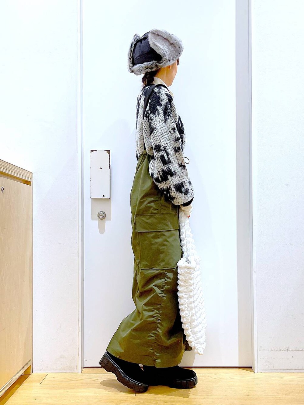 ホワイト系のトートバッグ、ベージュ系のTシャツ/カットソー、グリーン系のジャンパースカートを着用したレディースの冬コーディネートの4枚目の写真