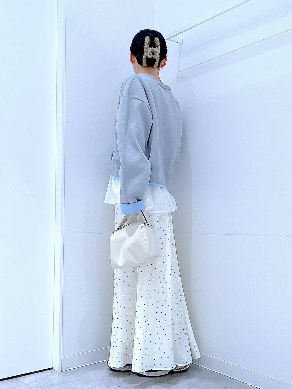 ホワイト系のショルダーバッグ、グレー系のカーディガン/ボレロ、ホワイト系のスカートを着用したレディースの春コーディネートの3枚目の写真