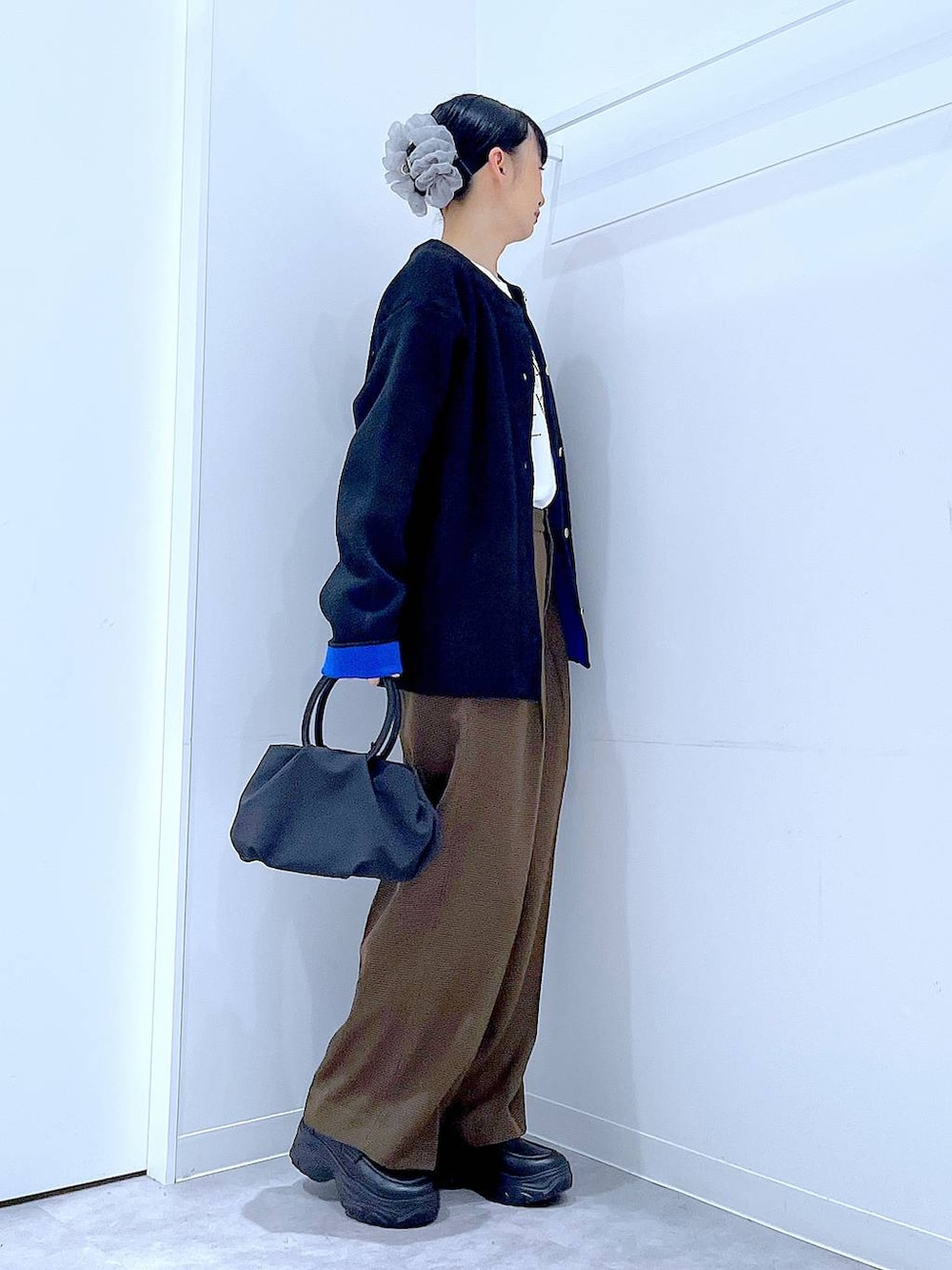 ブラック系のハンドバッグ、ブラウン系のスラックス、ホワイト系のTシャツ/カットソーを着用したレディースの秋コーディネートの4枚目の写真
