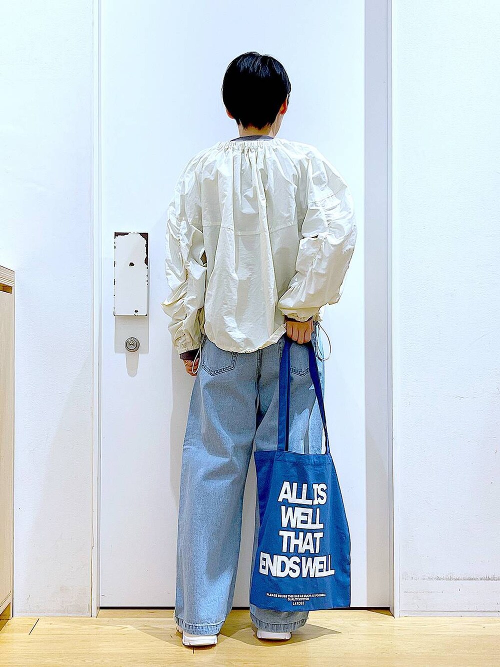 ホワイト系のスニーカー、ブルー系のデニムパンツ、ホワイト系のブルゾンを着用したレディースの春コーディネートの5枚目の写真