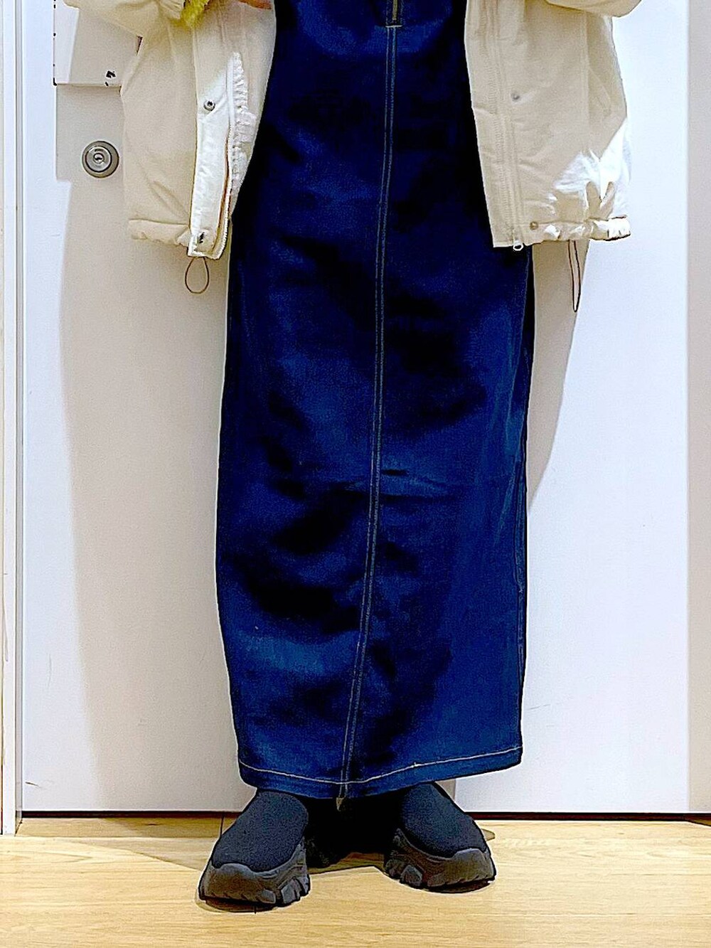 グリーン系のニット/セーター、ブルー系のジャンパースカート、ホワイト系のボディバッグ/ウエストポーチを着用したレディースの冬コーディネートの8枚目の写真