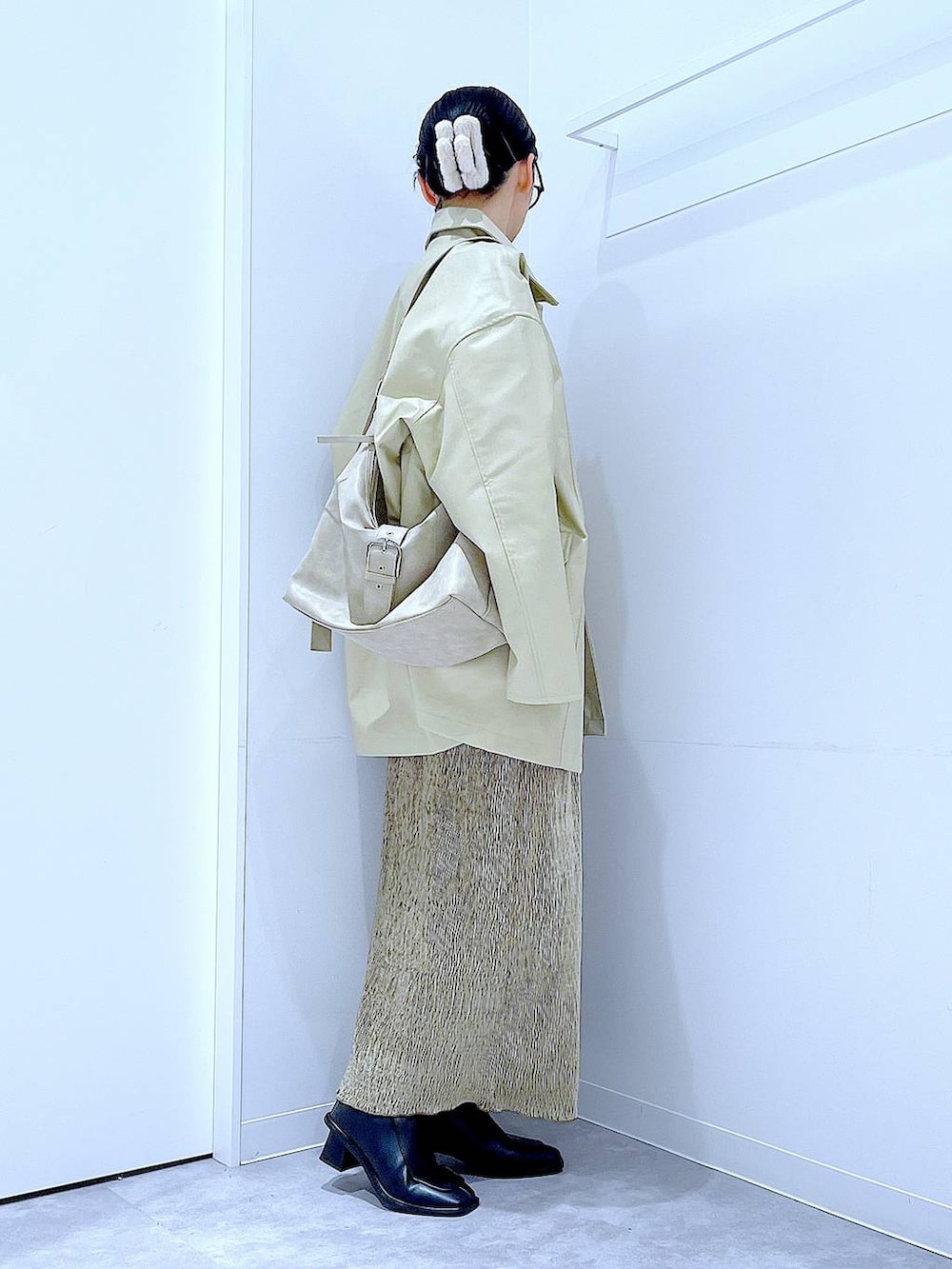 ベージュ系のステンカラーコート、ブラック系のブーツ、ホワイト系のショルダーバッグを着用したレディースの冬コーディネートの4枚目の写真