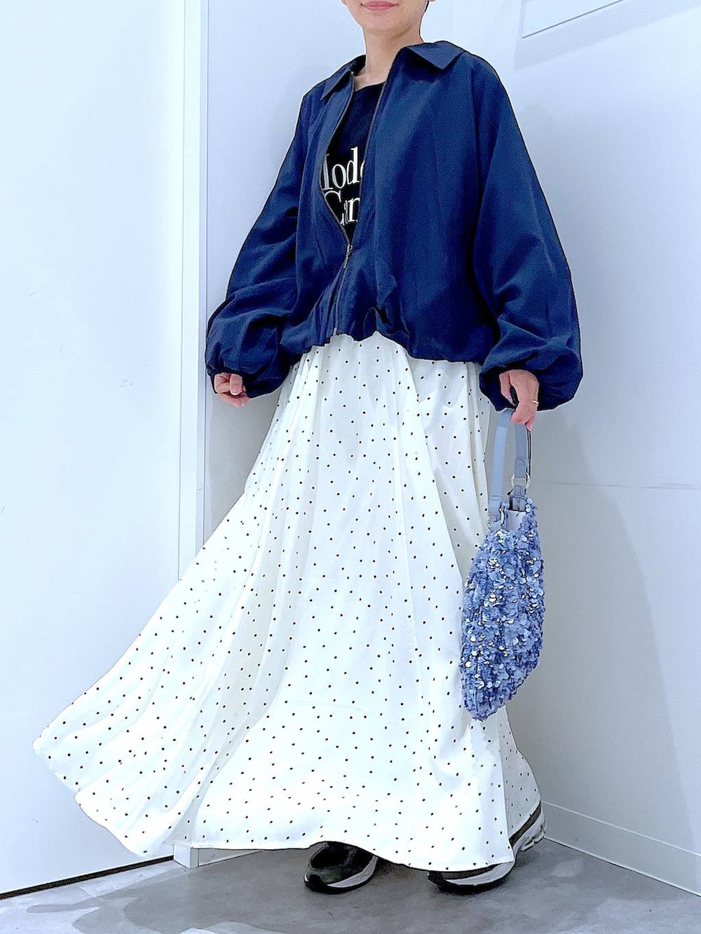 ブルー系のブルゾン、ブラック系のTシャツ/カットソー、ホワイト系のスカートを着用したレディースの春コーディネートの6枚目の写真