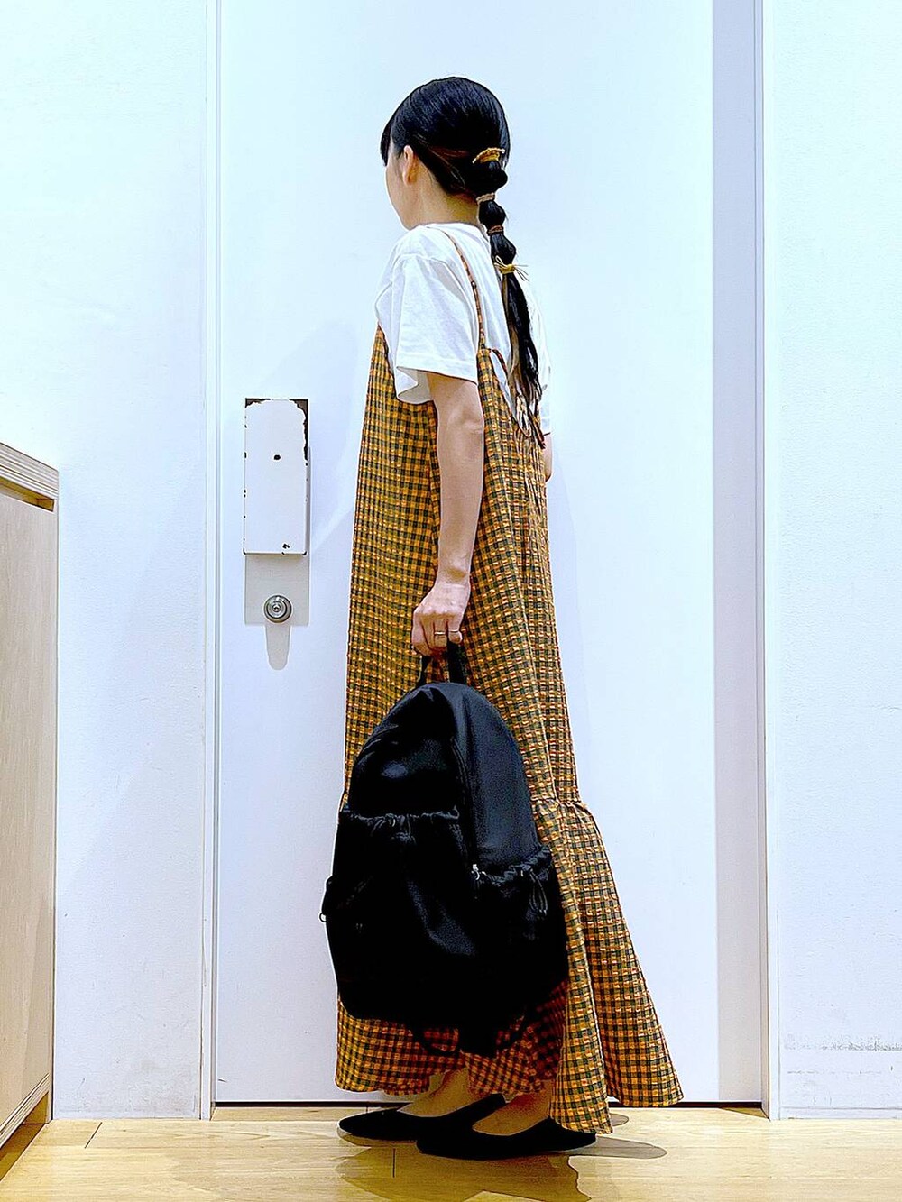 オレンジ系のワンピース、ブラック系のバックパック/リュック、ブラック系のパンプスを着用したレディースの春コーディネートの3枚目の写真