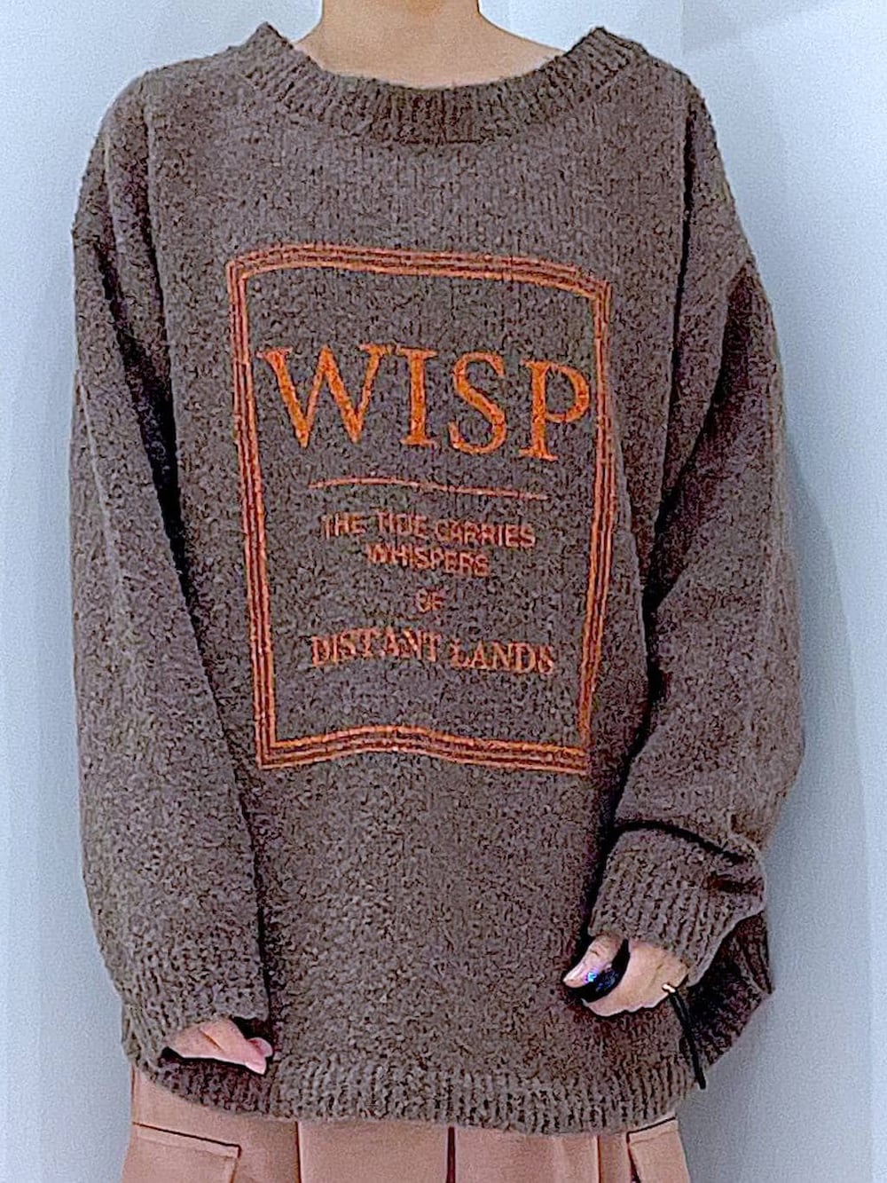 ブラウン系のニット/セーター、ブラック系のブーツ、ホワイト系のショルダーバッグを着用したレディースの冬コーディネートの7枚目の写真