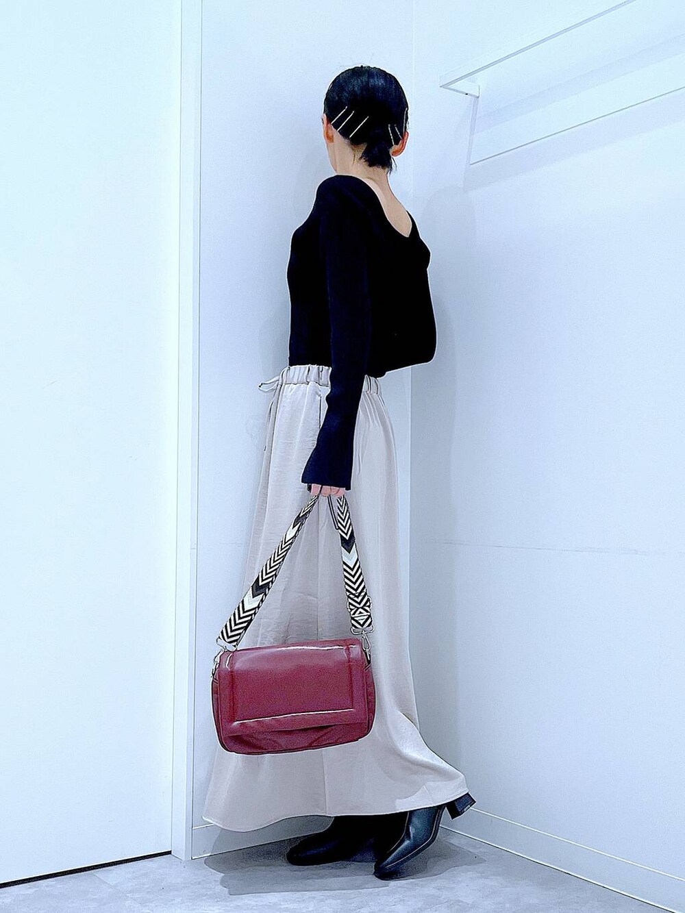 ブラック系のニット/セーター、ベージュ系のスカート、レッド系のショルダーバッグを着用したレディースの秋コーディネートの3枚目の写真