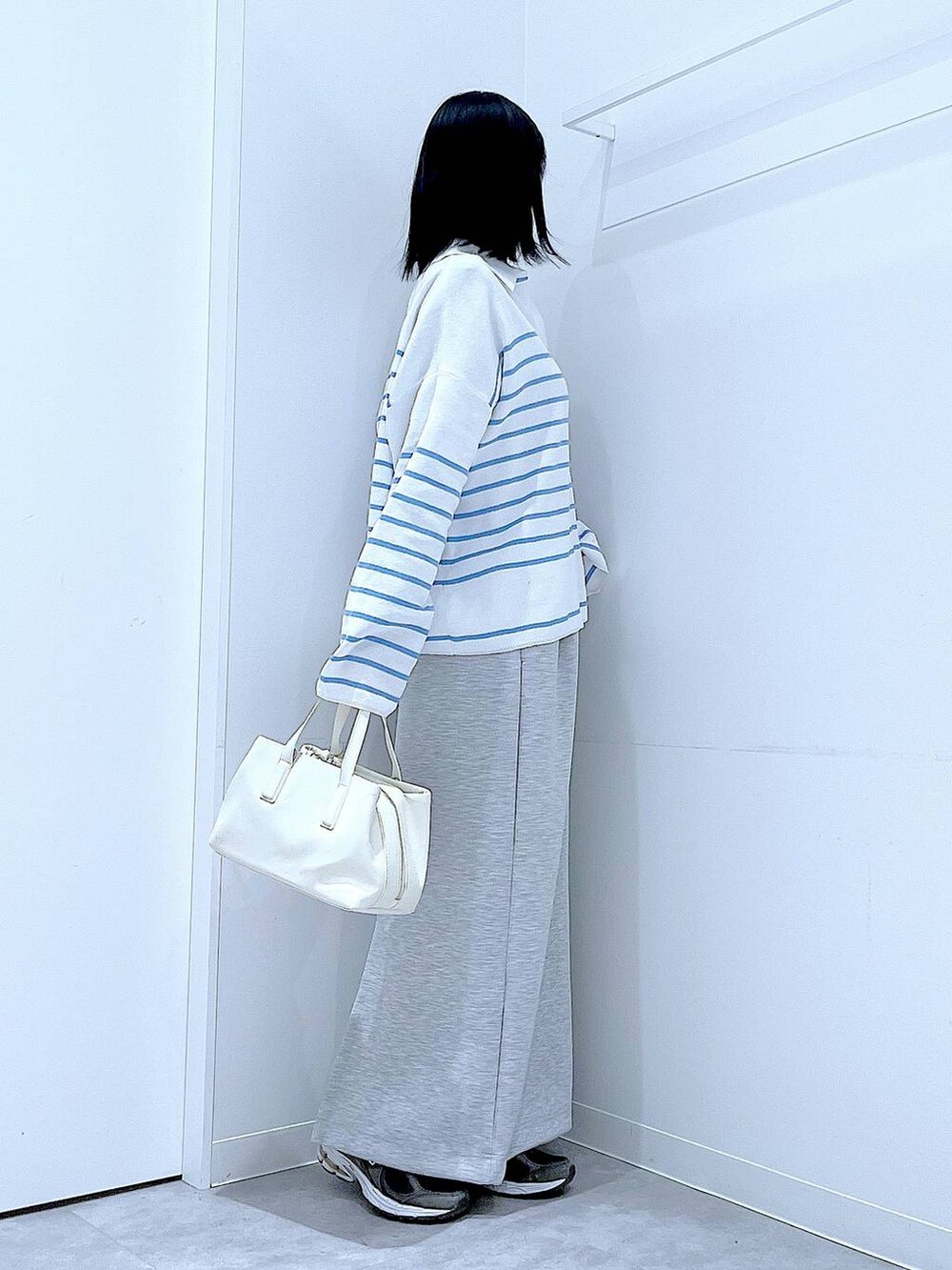 ホワイト系のボストンバッグ、グレー系のスカートを着用したレディースの春コーディネートの4枚目の写真