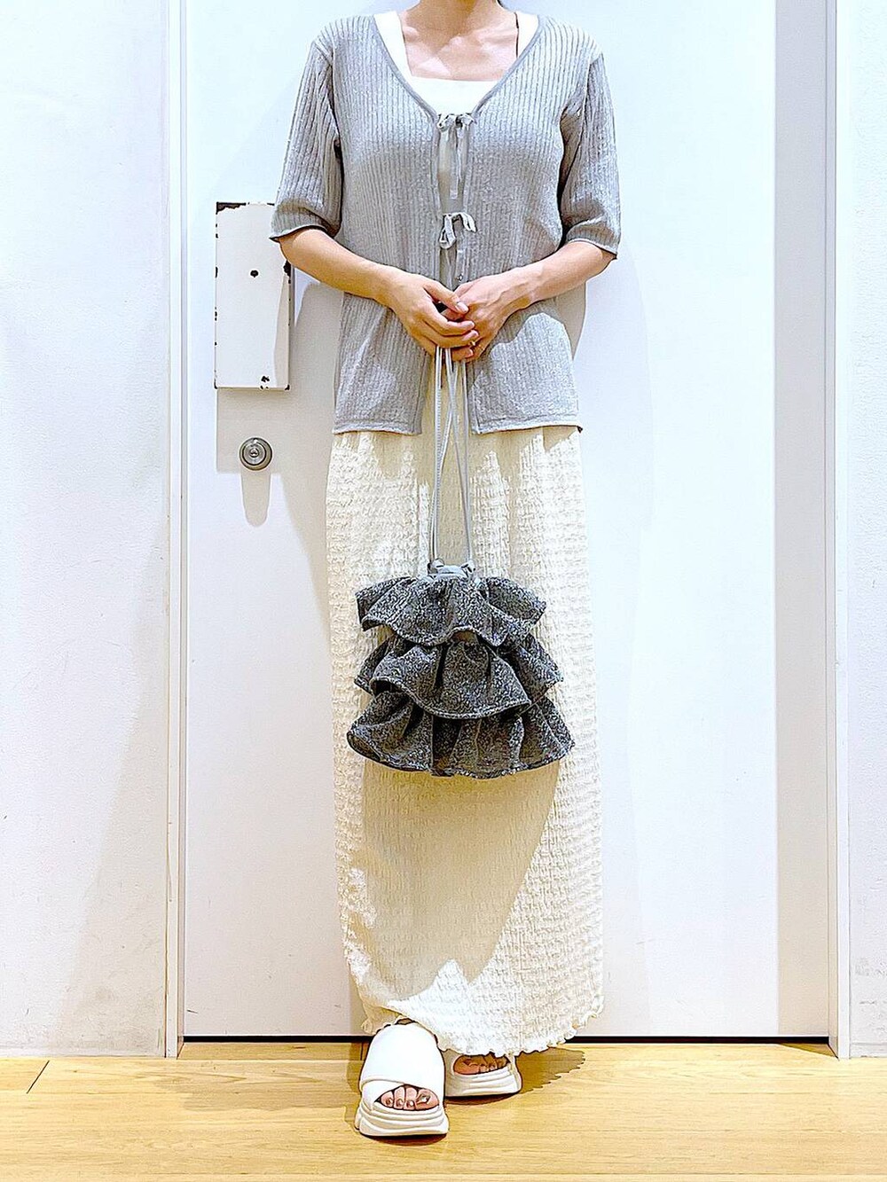 シルバー系のショルダーバッグ、ホワイト系のニット/セーター、ホワイト系のサンダルを着用したレディースの夏コーディネートの6枚目の写真