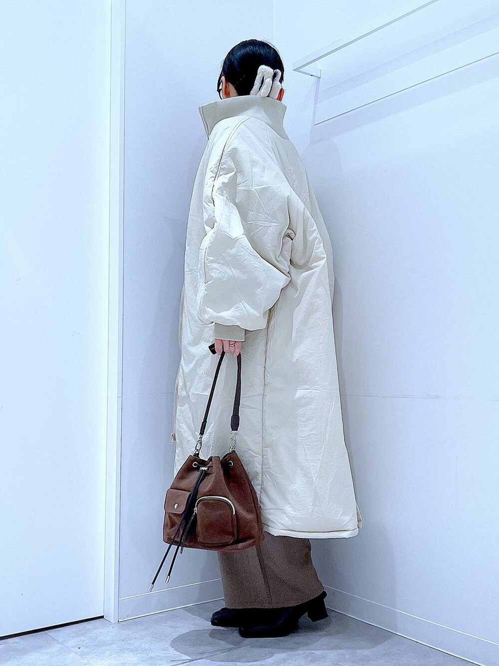 ホワイト系のブルゾン、ブラウン系のショルダーバッグ、ブラック系のブーツを着用したレディースの冬コーディネートの3枚目の写真