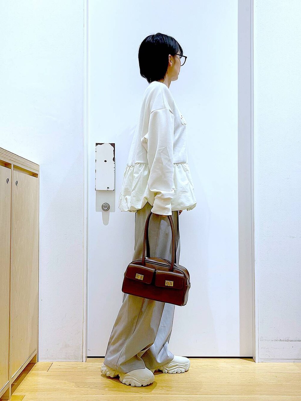 ブラウン系のハンドバッグ、ベージュ系のブーツ、ベージュ系のスウェットを着用したレディースの冬コーディネートの4枚目の写真