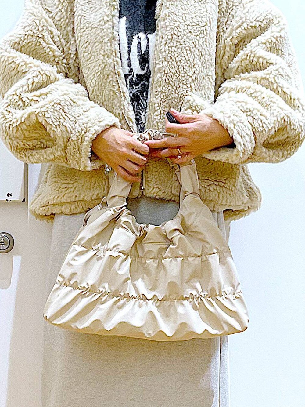 ホワイト系のブルゾン、ブラック系のブーツ、ベージュ系のスカートを着用したレディースの冬コーディネートの9枚目の写真