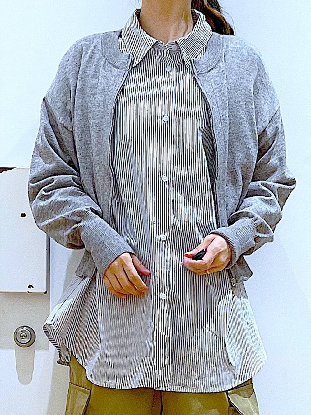 ブラック系のショルダーバッグ、グレー系のカーディガン/ボレロ、ブラック系のスニーカーを着用したレディースの春コーディネートの6枚目の写真